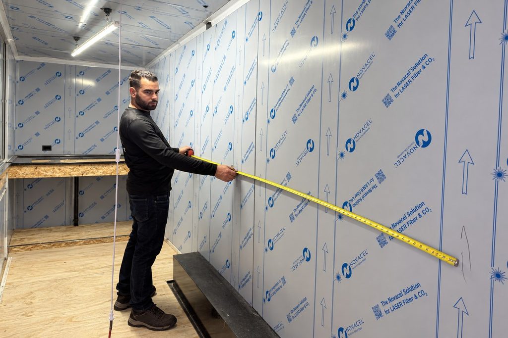 Commercial Kitchen Hood Installation: What to Prepare Before Requesting a Quote Technician measuring an interior wall of a mobile kitchen under construction.